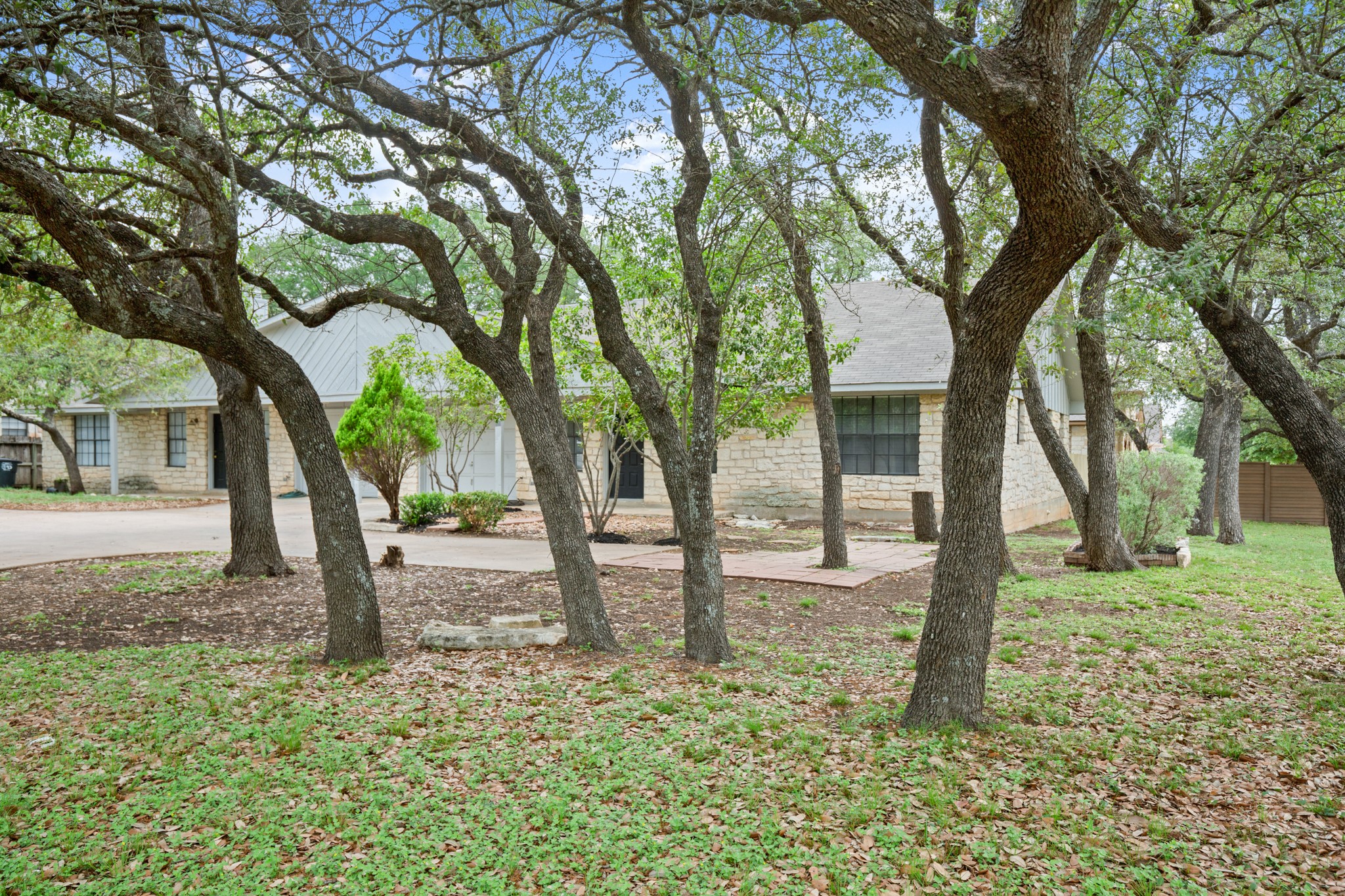 3801 Foust Trail, Unit B Georgetown, TX 78628 - Photo 27 of 31 The property features a stone exterior, a light-colored roof, and mature trees providing shade