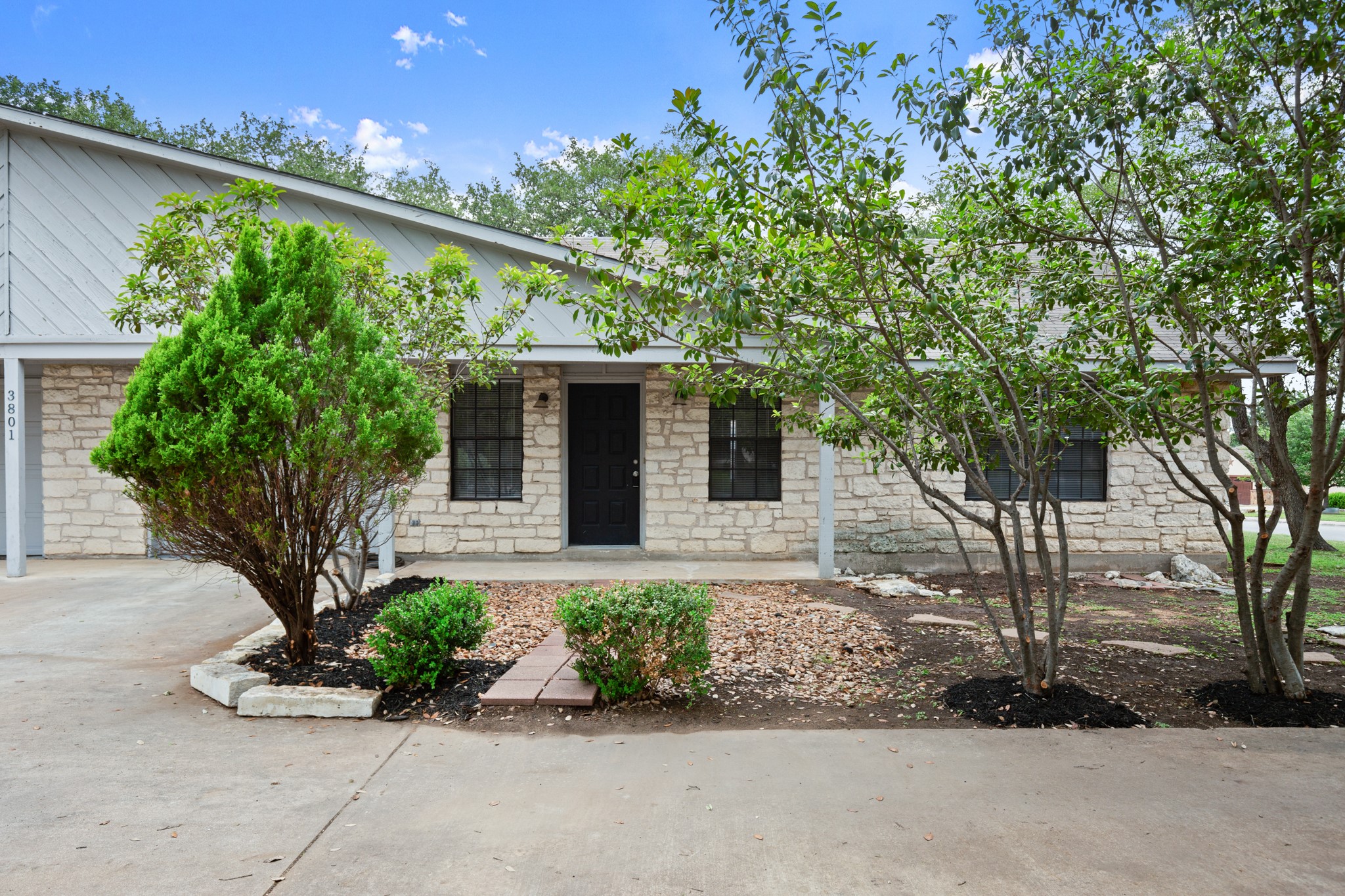 3801 Foust Trail, Unit B Georgetown, TX 78628 - Photo 3 of 31 The property exterior features a stone facade with a dark front door and black-framed windows