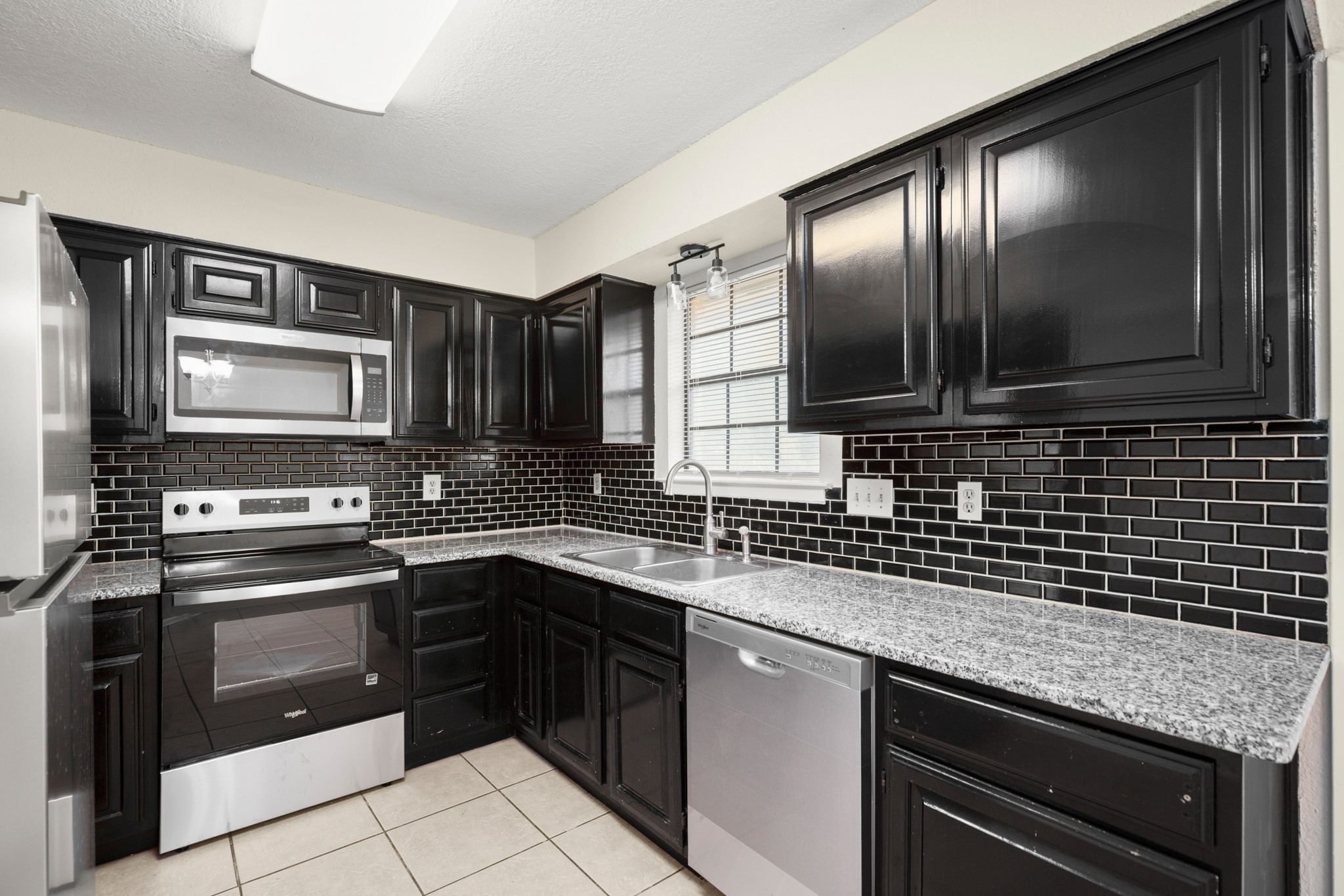 3801 Foust Trail, Unit B Georgetown, TX 78628 - Photo 4 of 31 The kitchen features black cabinetry, a black subway tile backsplash, and light-colored countertops