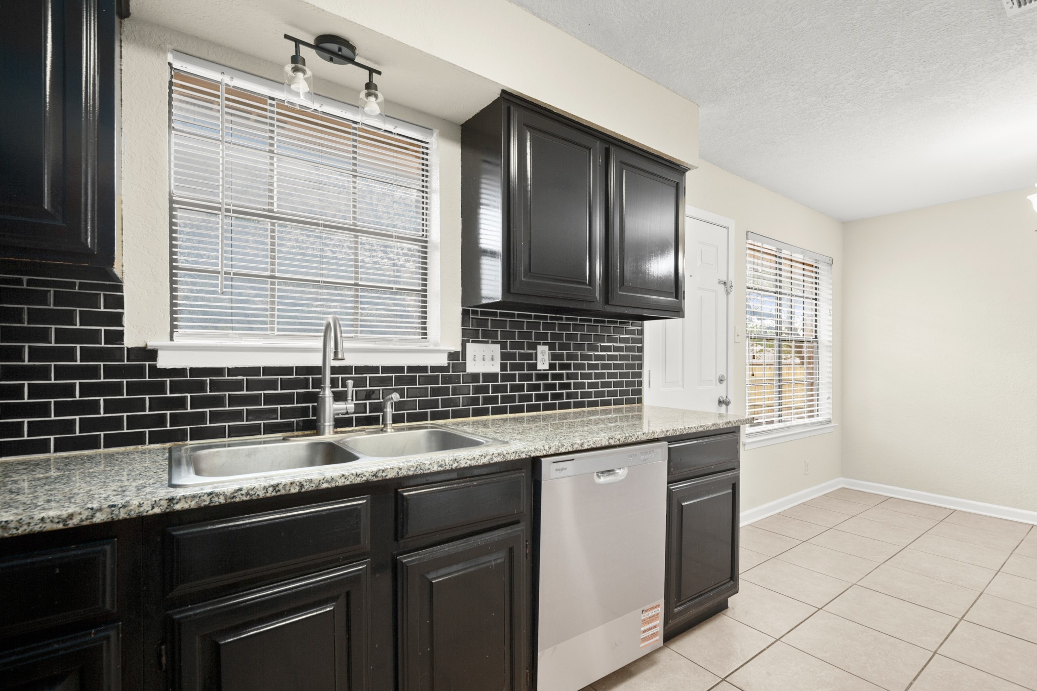 3801 Foust Trail, Unit B Georgetown, TX 78628 - Photo 5 of 31 The kitchen features dark cabinetry, a black subway tile backsplash, granite countertops, and a dual basin sink with a chrome faucet