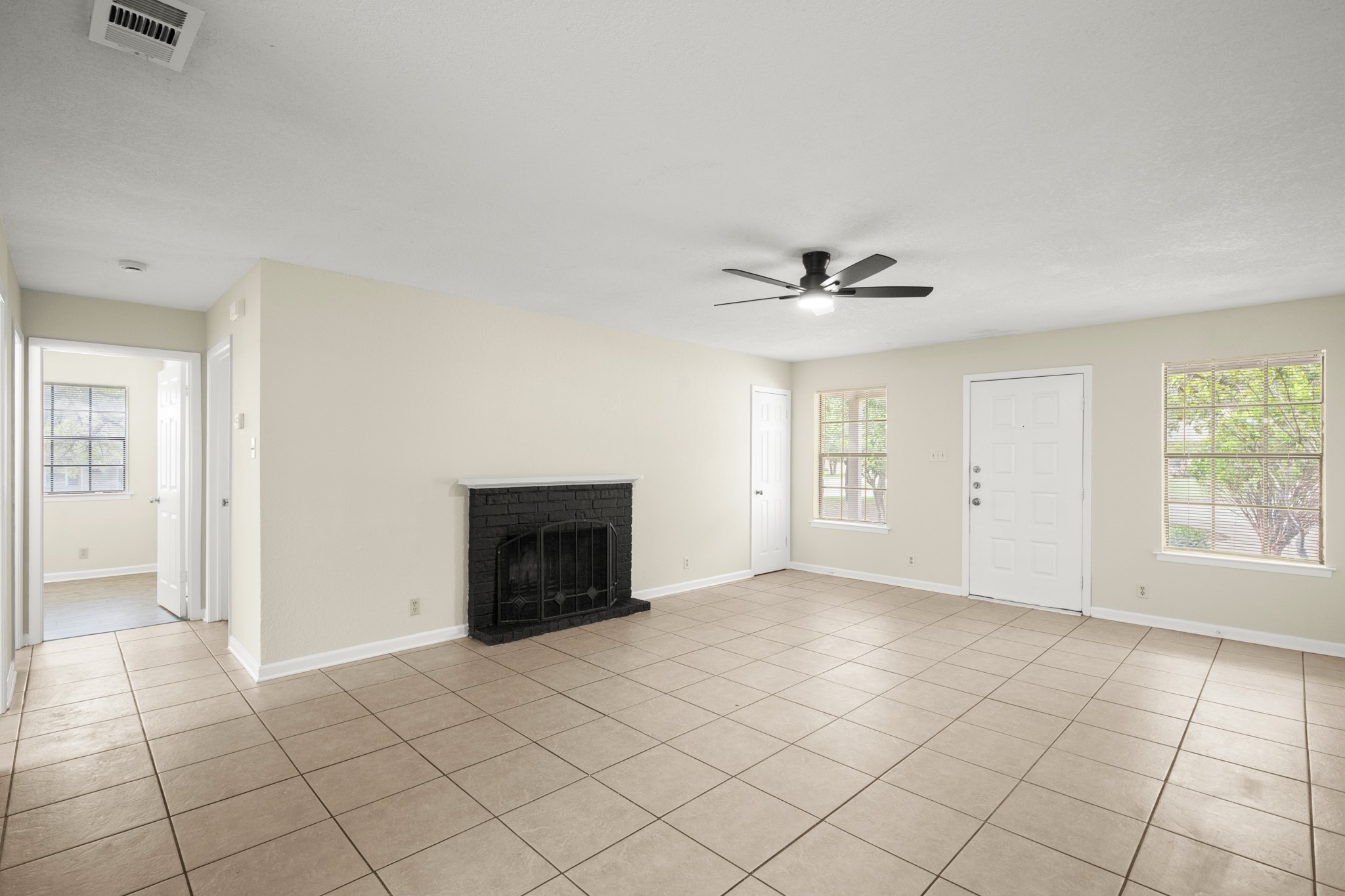3801 Foust Trail, Unit B Georgetown, TX 78628 - Photo 8 of 31 Bright living area featuring tiled flooring, a fireplace with a black painted brick surround, and a ceiling fan with integrated lighting