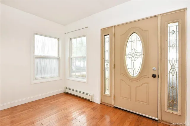 an empty room with wooden floor mirror and windows