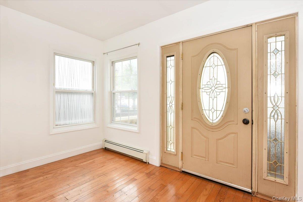 81-35 166th Street Queens, NY 11432 - Photo 5 of 34 an empty room with wooden floor mirror and windows