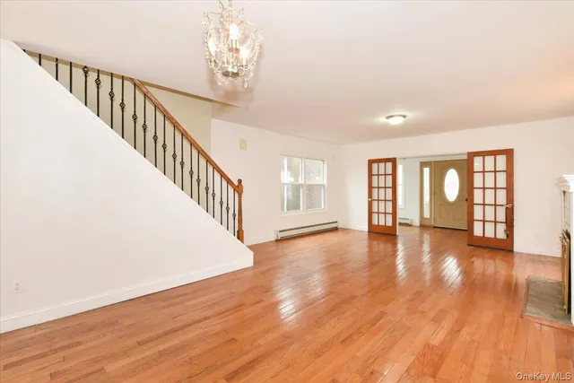 a view of an empty room with wooden floor and fan