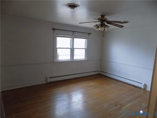 an empty room with wooden floor fan and windows