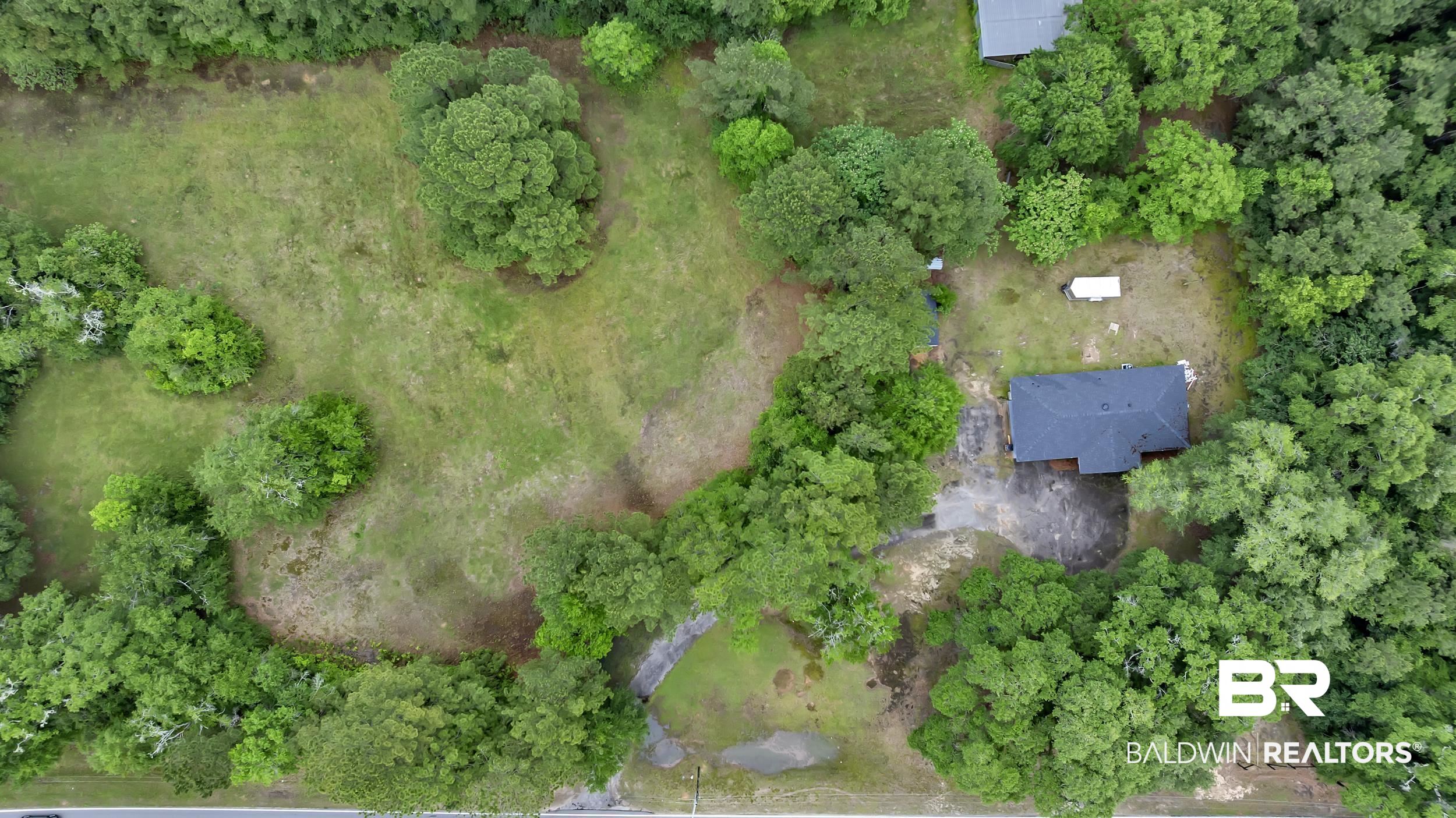 2712 Shelton Beach Rd Extension Mobile, AL 36613 - Photo 24 of 24 Aerial property overview featuring wooded surroundings and an open grassy area