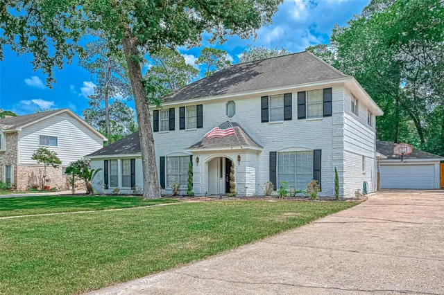 a front view of a house with a garden and trees