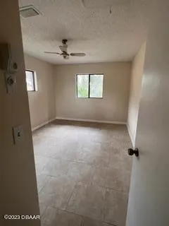 an empty room with windows and fan