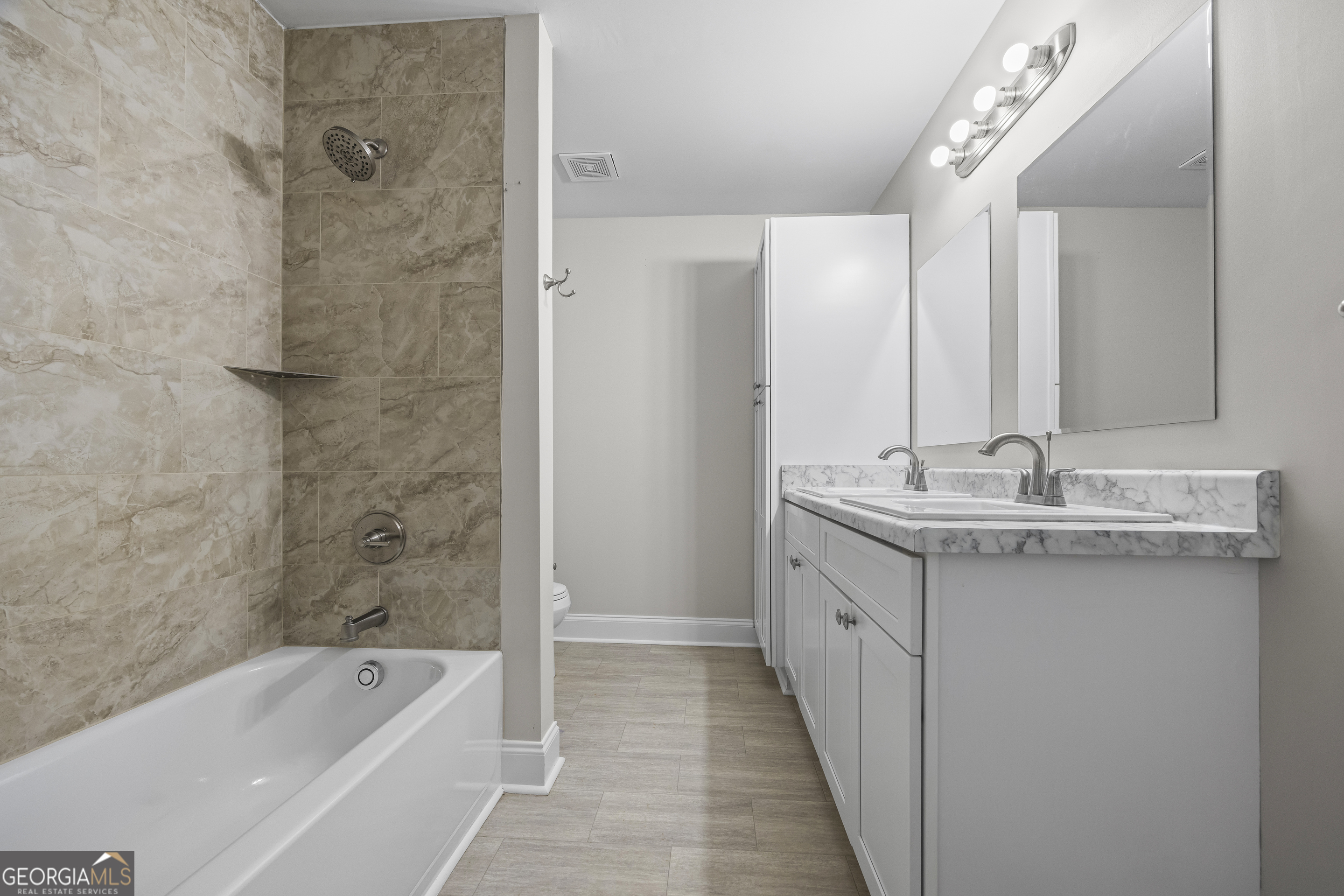 9750 Lavonia Road Carnesville, GA 30521 - Photo 28 of 49 a bathroom with a double vanity sink and mirror with bathtub