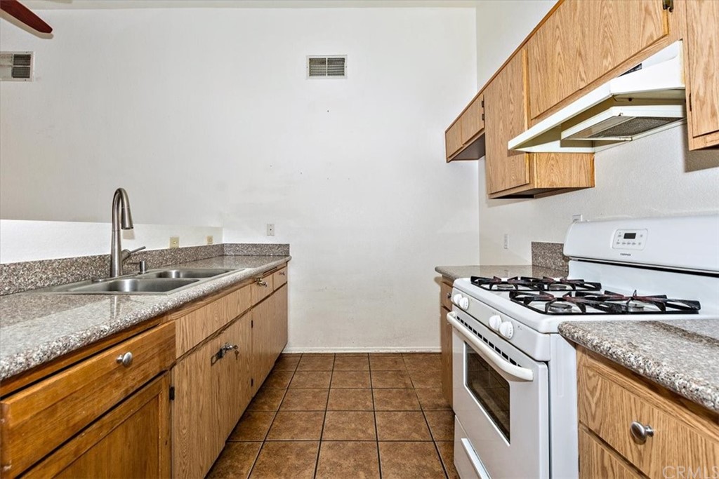14560 Juniper Lane Adelanto, CA 92301 - Photo 9 of 25 a kitchen with granite countertop a sink and a stove