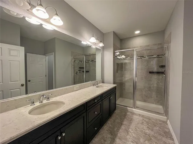 a bathroom with a double vanity sink mirror and shower