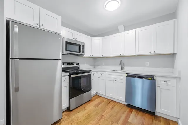 a kitchen with white cabinets stainless steel appliances and sink