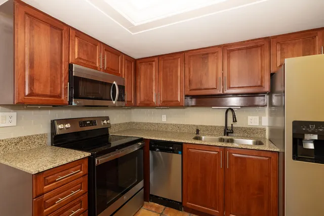 a kitchen with stainless steel appliances granite countertop a refrigerator stove top oven a sink and dishwasher