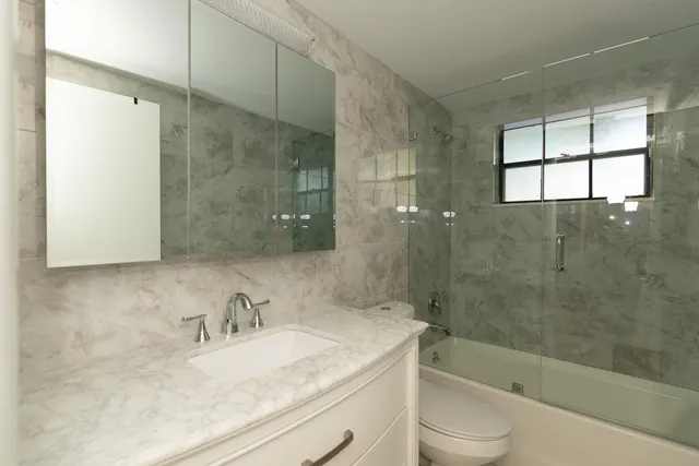 a bathroom with a granite countertop sink toilet and shower