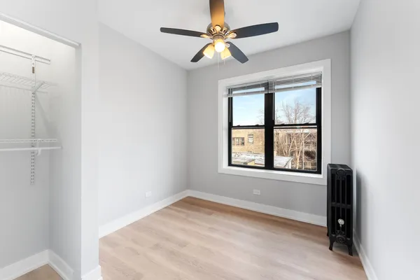 an empty room with a window and a fan