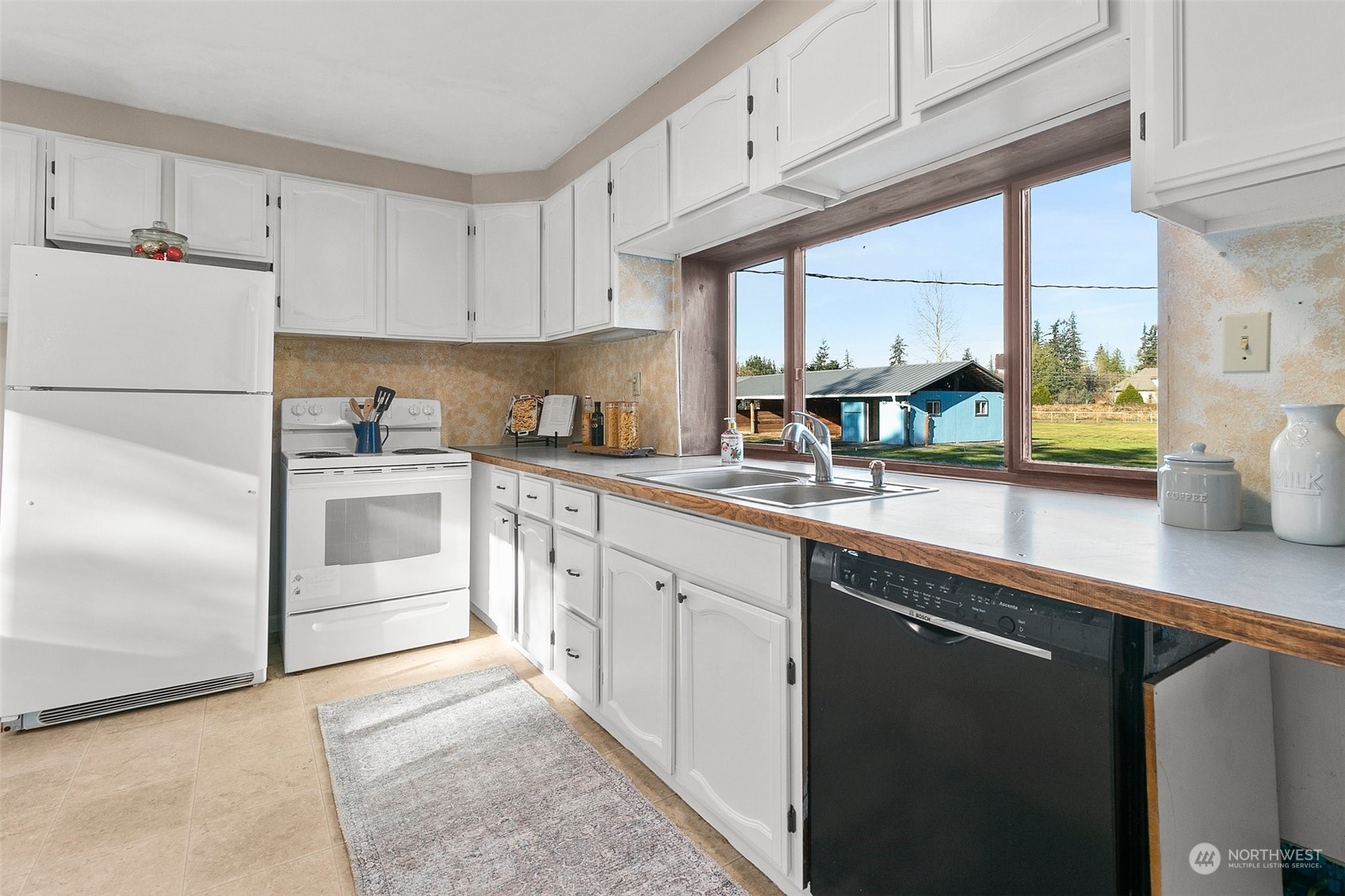 21650 Sweeney Road Southeast Maple Valley, WA 98038 - Photo 10 of 36 a kitchen with stainless steel appliances a sink a stove and white cabinets
