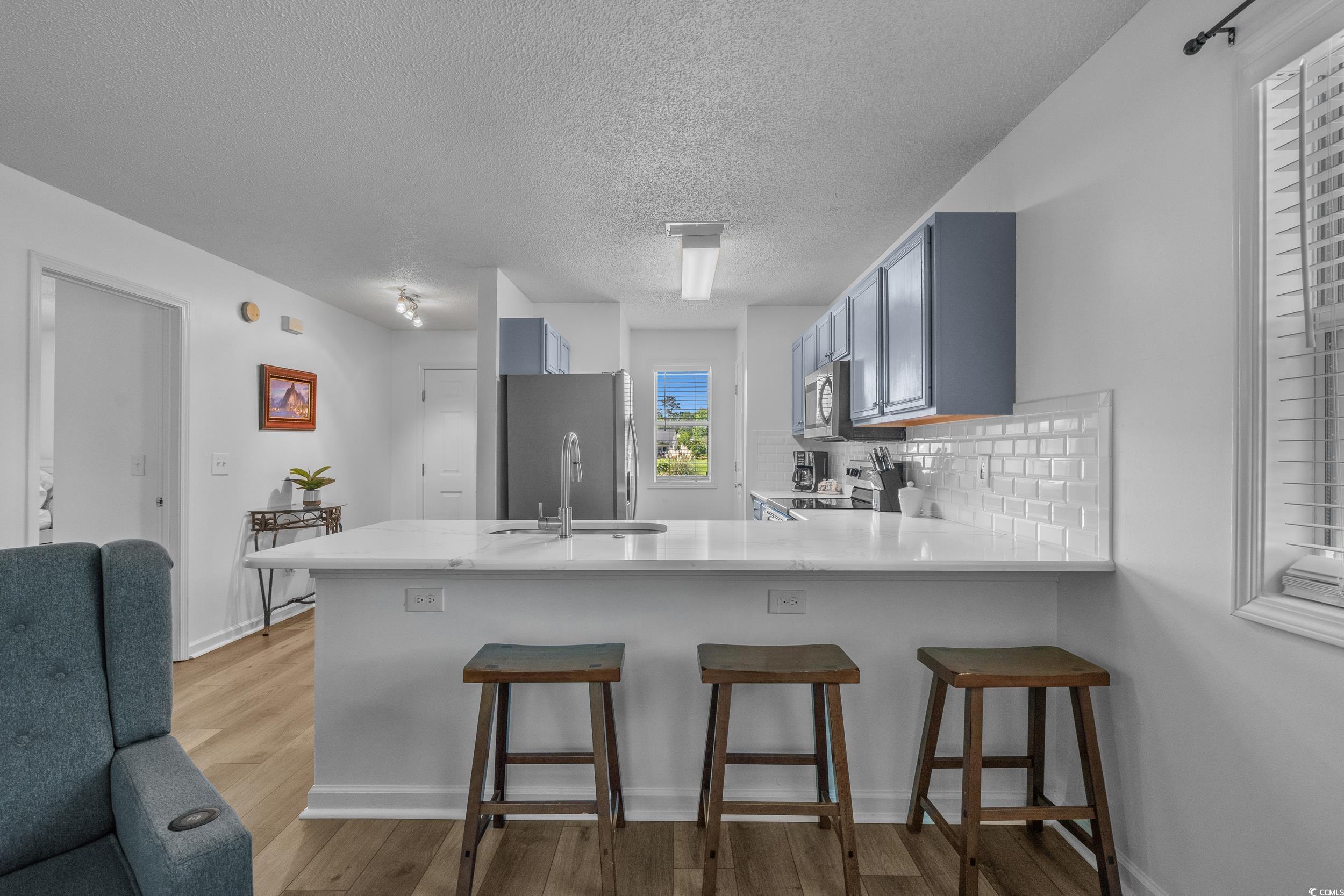 1290 White Tree Lane Myrtle Beach, SC 29588 - Photo 10 of 33 Living area with ceiling fan, a textured ceiling, and light wood-style flooring