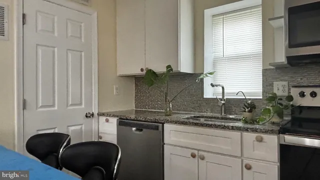 a kitchen with granite countertop a sink a stove and cabinets