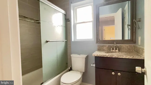 a bathroom with a granite countertop sink toilet and shower