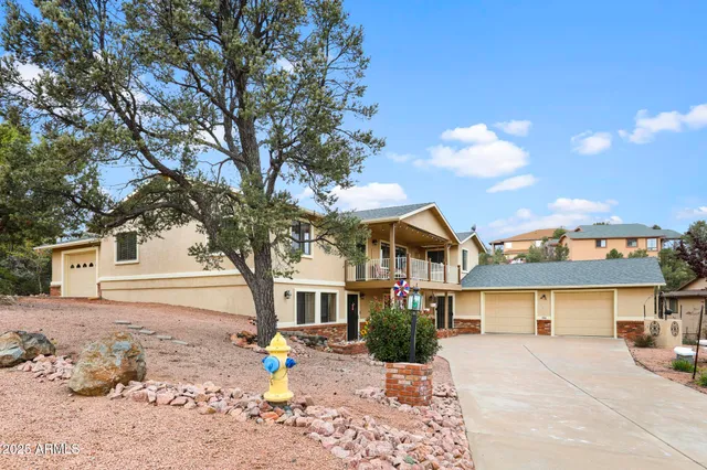 a front view of a house with a dirt yard and a large tree