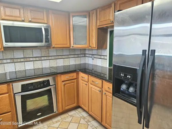 a kitchen with stainless steel appliances granite countertop a refrigerator a stove a sink and a microwave
