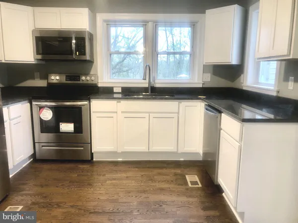 a kitchen with granite countertop a stove a sink and a microwave