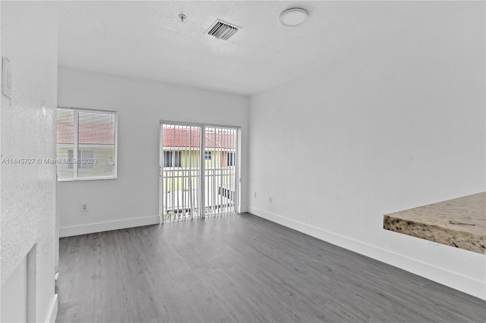 7989 Northwest 8th Street, Unit 110 Miami, FL 33126 - Photo 11 of 24 an empty room with wooden floor and windows