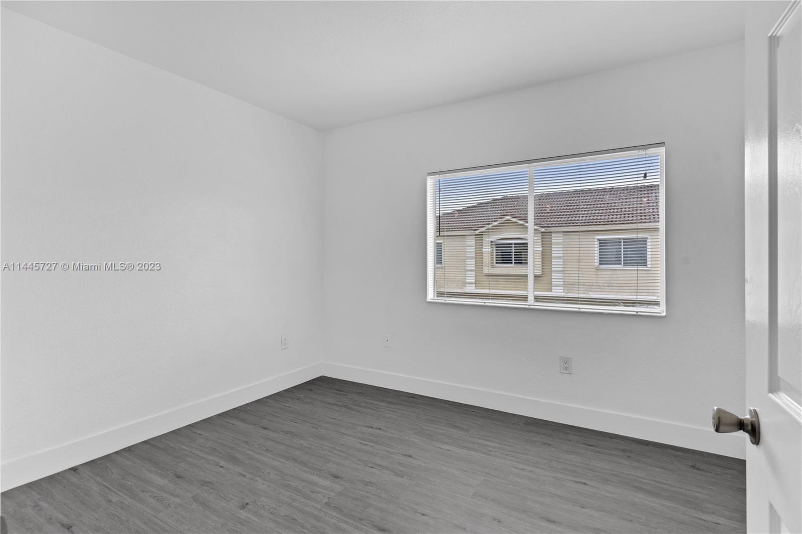 7989 Northwest 8th Street, Unit 110 Miami, FL 33126 - Photo 15 of 24 a view of an empty room with wooden floor and a window