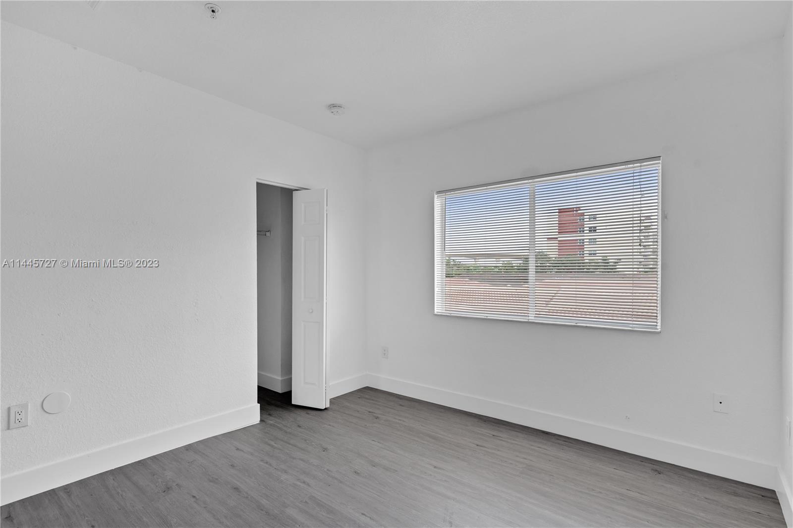7989 Northwest 8th Street, Unit 110 Miami, FL 33126 - Photo 21 of 24 a view of an empty room with wooden floor and a window