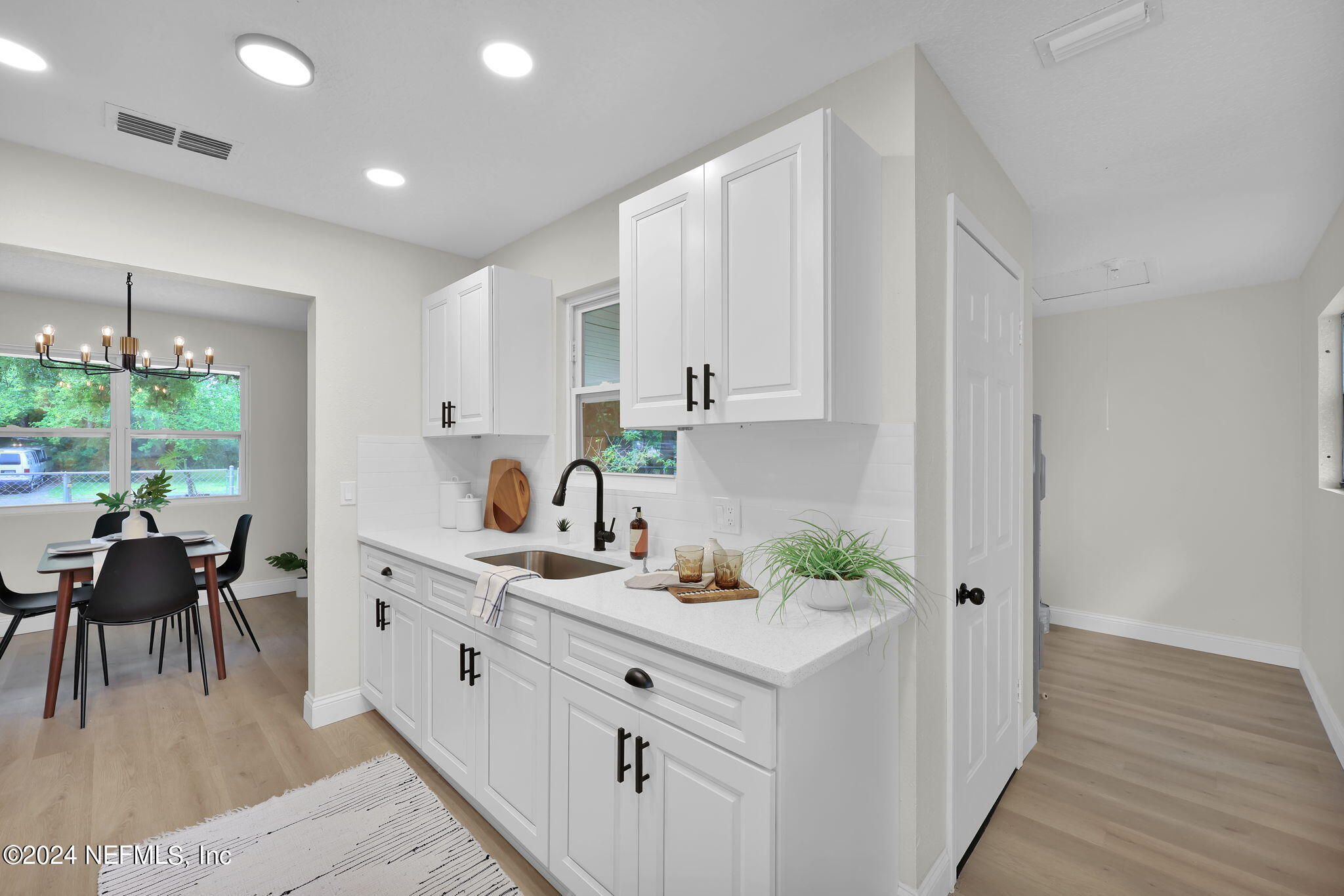 a kitchen with white cabinets and wooden floor
