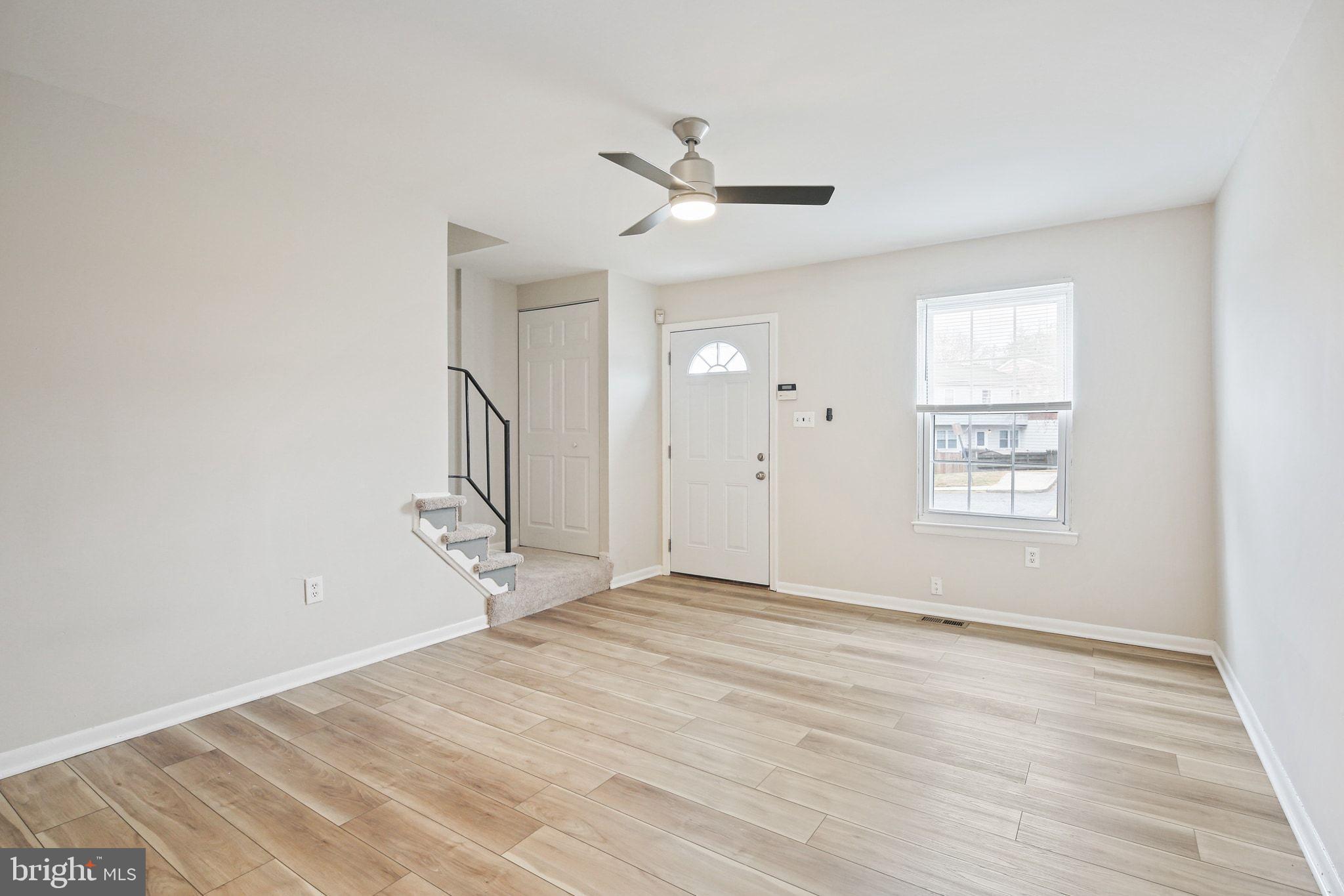 8209 Stewarton Court Severn, MD 21144 - Photo 4 of 34 an empty room with wooden floor ceiling fan and windows