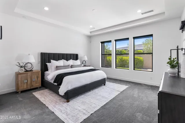 a bed sitting in a spacious bedroom next to a window