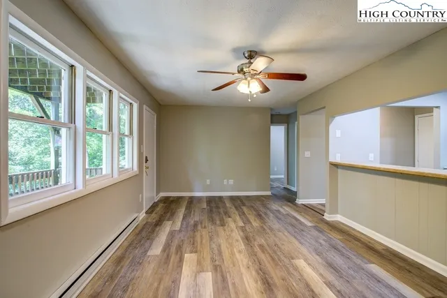a view of empty room with wooden floor and fan