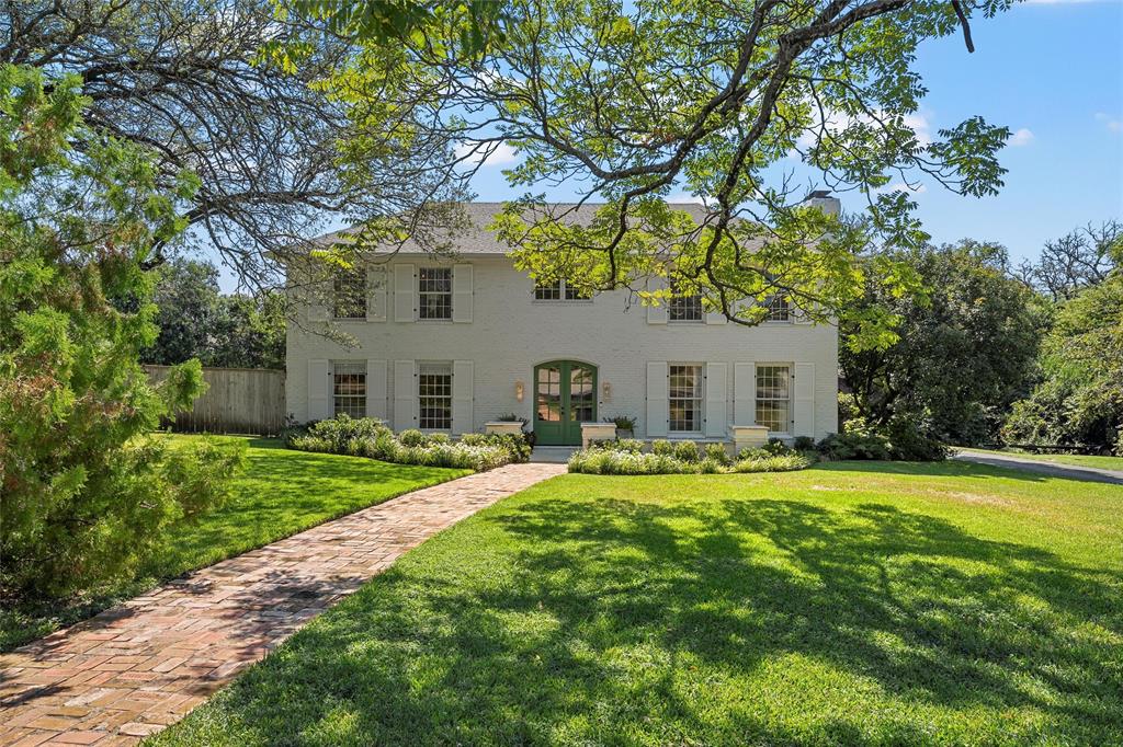 a front view of a house with garden and trees