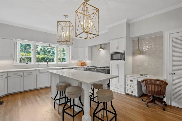 a kitchen with stainless steel appliances a kitchen island hardwood floor and a sink