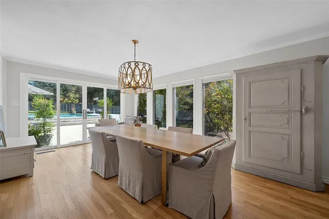a dining room with wooden floor a chandelier a wooden table and chairs