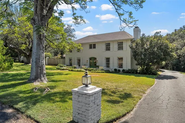 a view of house that has a big yard with large trees