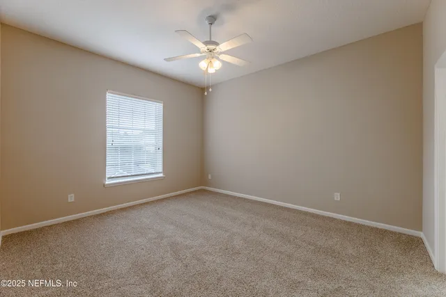 an empty room with windows and chandelier fan