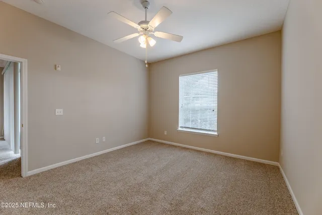 an empty room with windows and fan