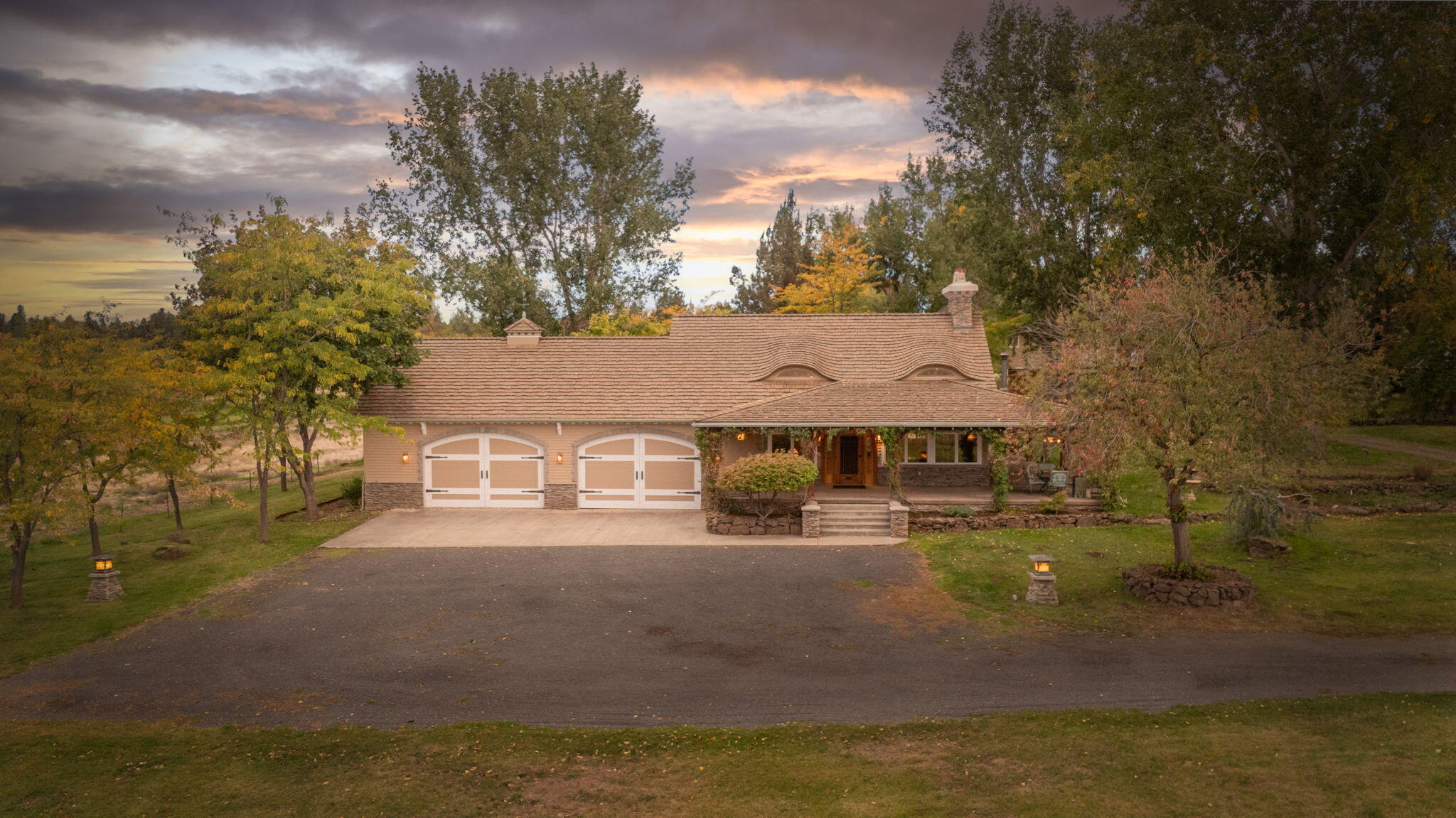 21925 Bear Creek Road Bend, OR 97702 - Photo 3 of 104 Front of the house at sunset w/4 car garage and mature trees