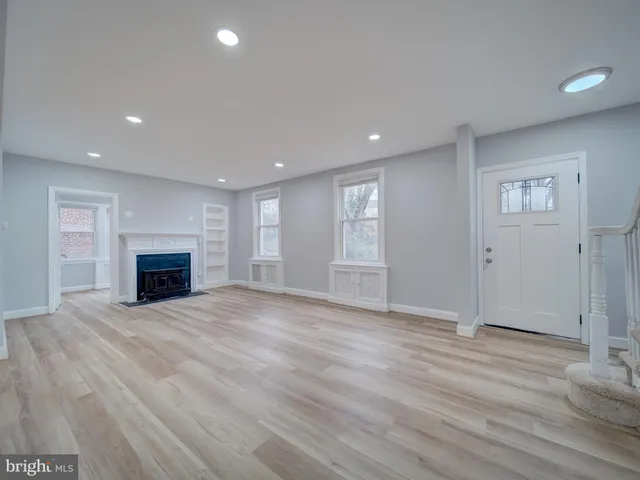 an empty room with wooden floor fireplace and windows