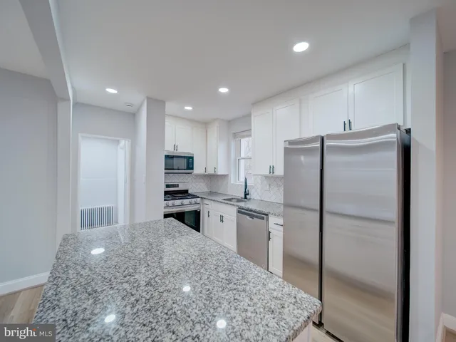 a kitchen with stainless steel appliances granite countertop a refrigerator and a stove top oven