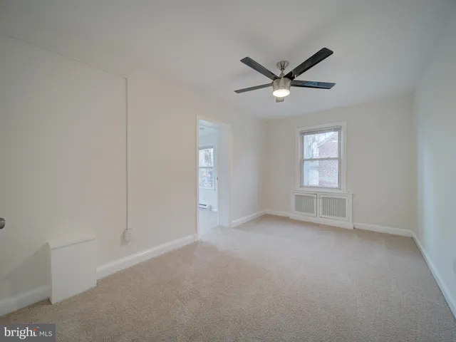 an empty room with a window and a fan