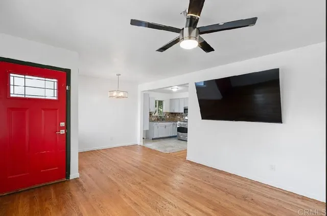 a view of a livingroom with a flat screen tv wooden floor and a ceiling fan