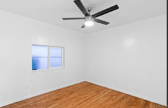 an empty room with a window and ceiling fan