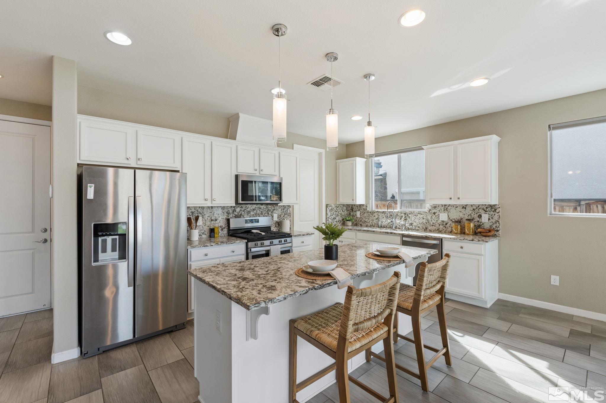 3025 Ethelinda Way Reno, NV 89521 - Photo 8 of 31 a kitchen with stainless steel appliances kitchen island granite countertop a refrigerator a stove a sink a dining table and chairs
