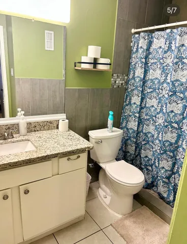 a bathroom with a granite countertop toilet sink and mirror