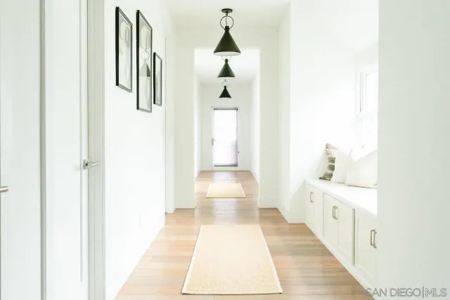 a hallway with white cabinets and wooden floor