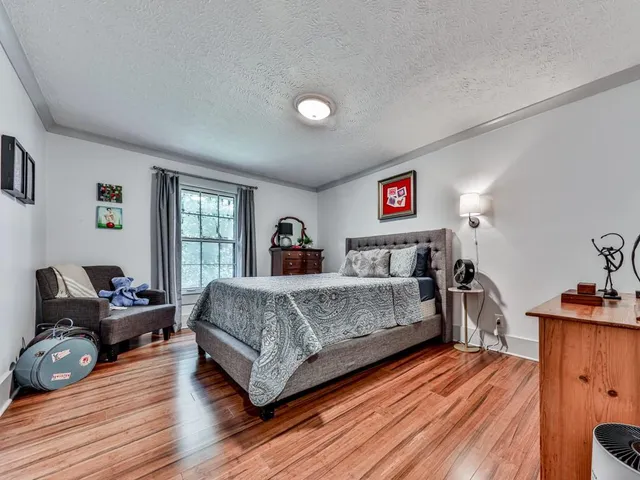 a spacious bedroom with a bed and wooden floor