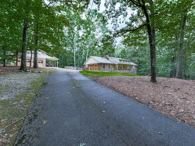 a view of a house with a yard and large trees